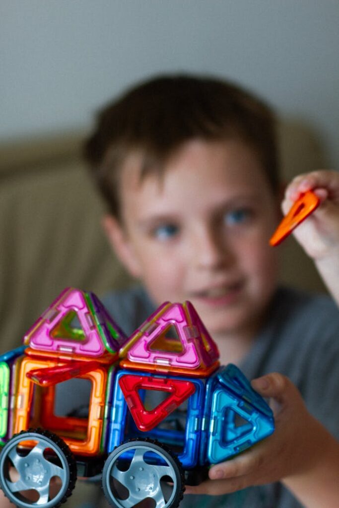 pexels-photo-17428579 Hand holding Colorful Vehicle Toy over Boy